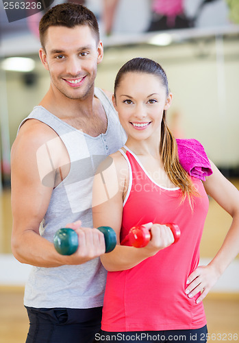 Image of two smiling people working out with dumbbells