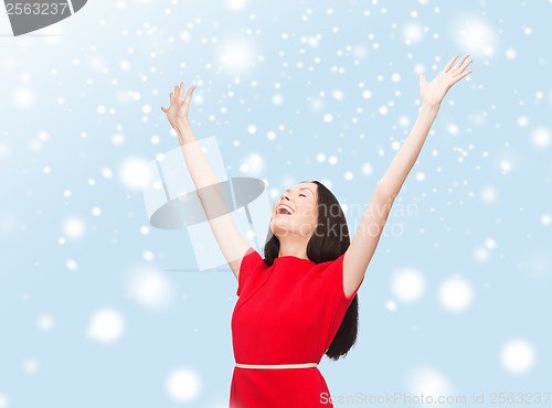 Image of smiling young woman in red dress waving hands