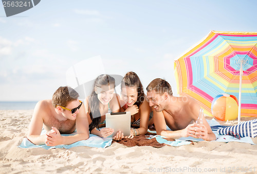 Image of group of smiling people with tablet pc on beach