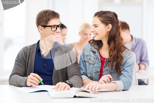 Image of two teenagers with notebooks and book at school