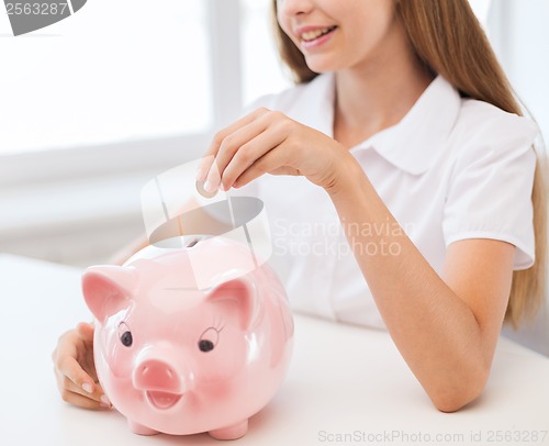 Image of smiling child putting coin into big piggy bank