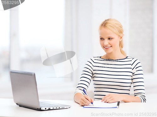 Image of smiling student with laptop computer and documents