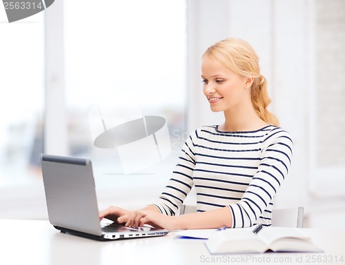Image of smiling student with laptop computer and notebook
