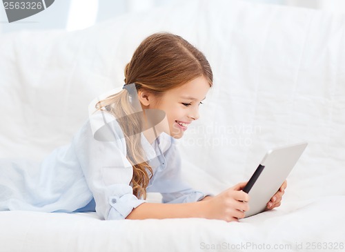 Image of smiling girl with tablet computer at home