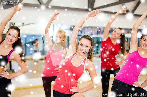 Image of group of smiling people stretching in the gym