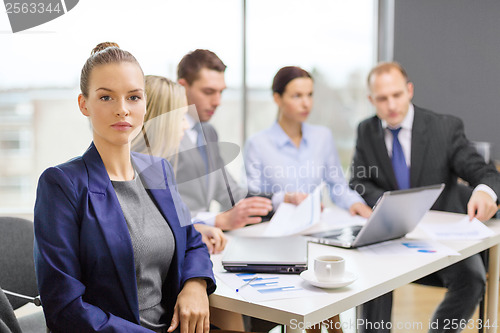 Image of businesswoman in office with team on the back