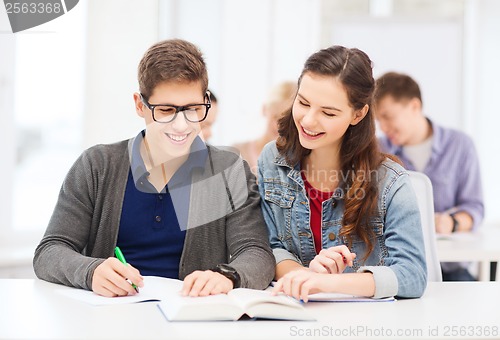 Image of two teenagers with notebooks and book at school