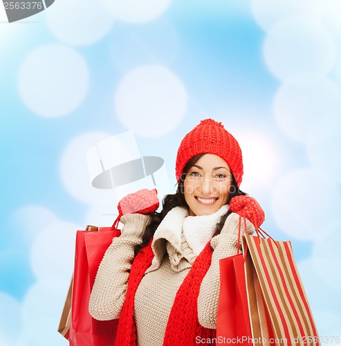 Image of smiling woman in warm clothers with shopping bags