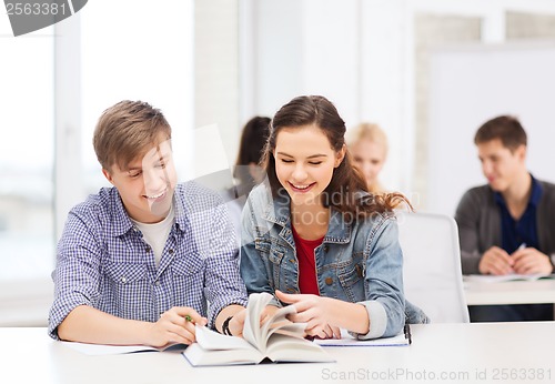 Image of two teenagers with notebooks and book at school