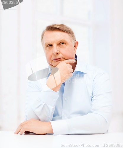 Image of stressed old man holding head at home