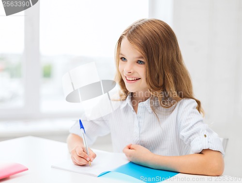 Image of student girl writing in notebook at school