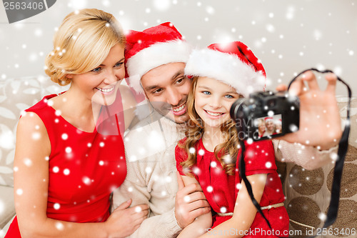 Image of smiling family in santa helper hats taking picture