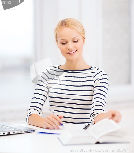 Image of smiling student with laptop computer and documents