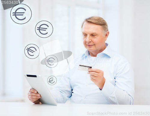 Image of old man with tablet pc and credit card at home