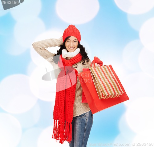 Image of smiling woman in warm clothers with shopping bags