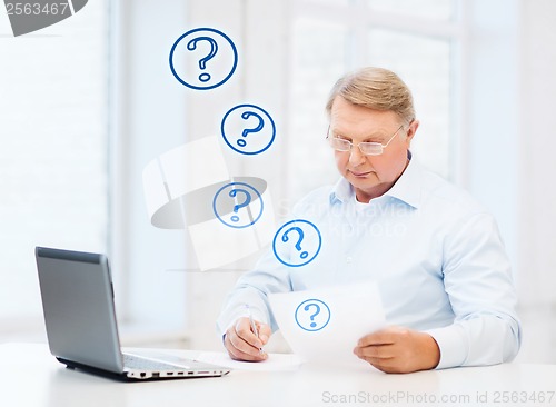 Image of old man in eyeglasses filling a form at home