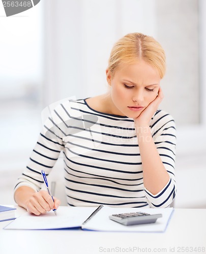 Image of woman with notebook and calculator studying