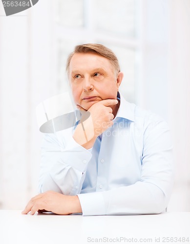 Image of stressed old man holding head at home