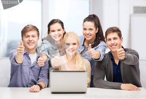 Image of smiling students with laptop showing thumbs up