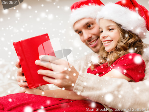 Image of smiling father and daughter reading book