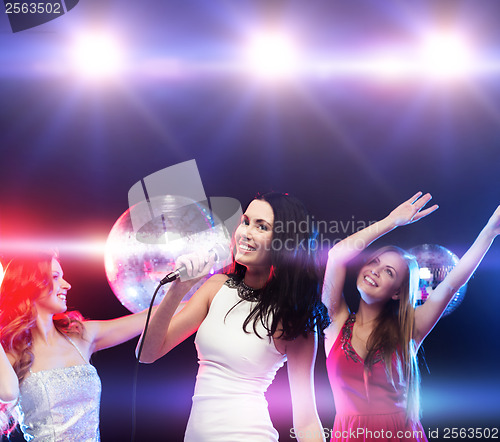 Image of three smiling women dancing and singing karaoke