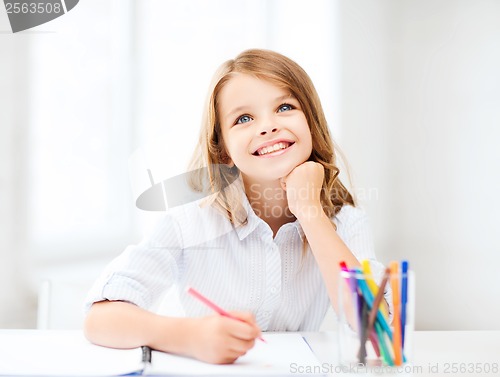 Image of smiling little student girl drawing at school