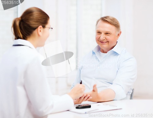 Image of female doctor or nurse measuring blood sugar value