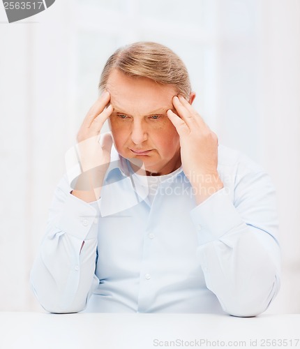 Image of stressed old man holding head at home