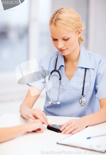 Image of female doctor or nurse measuring blood sugar value