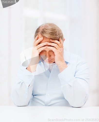 Image of stressed old man holding head at home