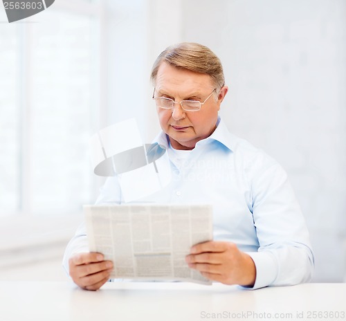 Image of old man at home reading newspaper