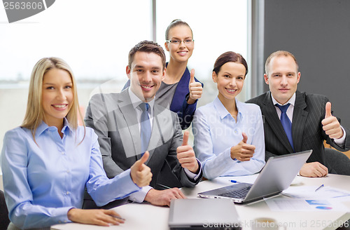 Image of business team showing thumbs up in office