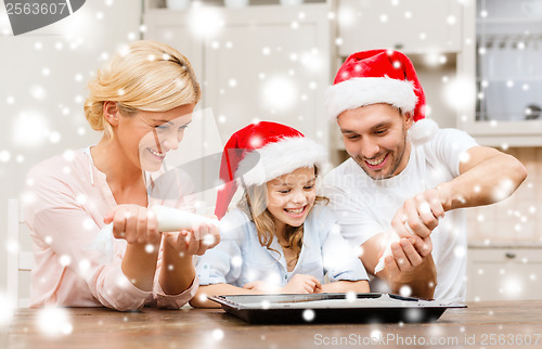 Image of happy family in santa helper hats making cookies