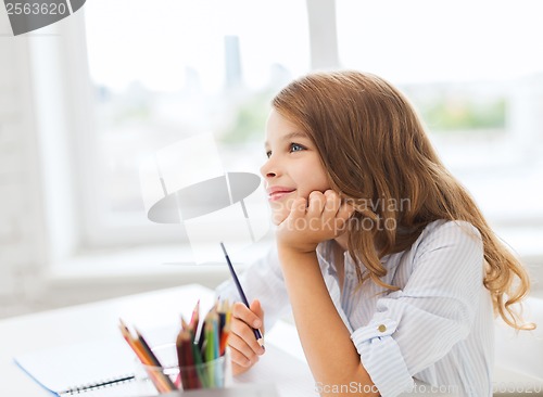 Image of little student girl drawing and dreaming at school