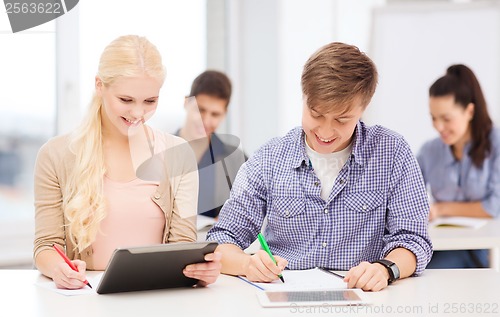 Image of two smiling students with tablet pc and notebooks