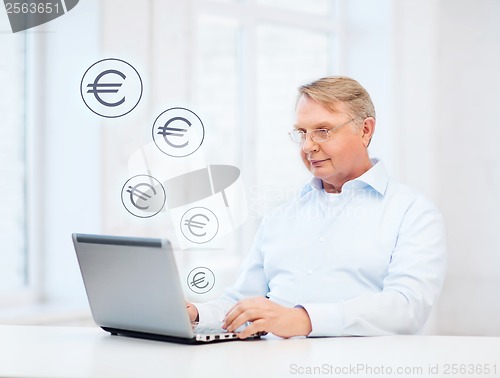 Image of old man in eyeglasses working with laptop at home