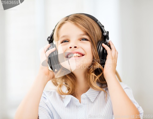 Image of smiling little girl with headphones at home