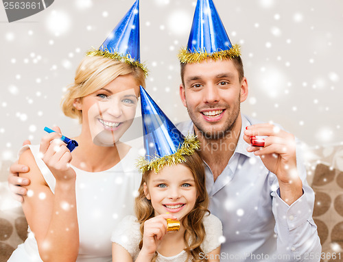 Image of smiling family in blue hats blowing favor horns