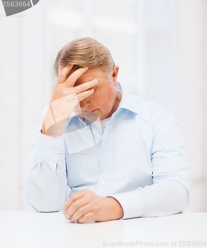 Image of stressed old man holding head at home