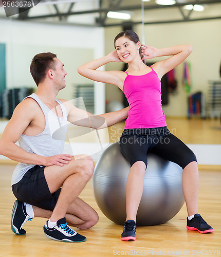 Image of male trainer with woman doing crunches on the ball