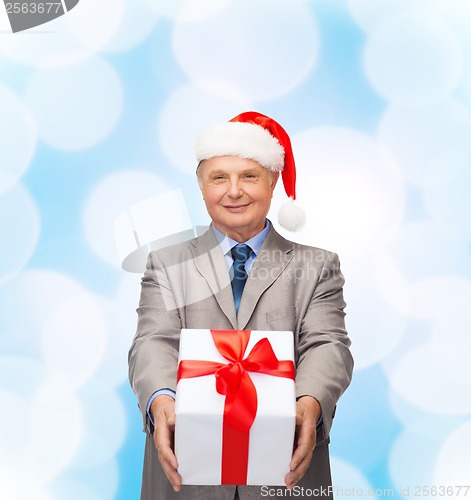 Image of smiling man in suit and santa helper hat with gift