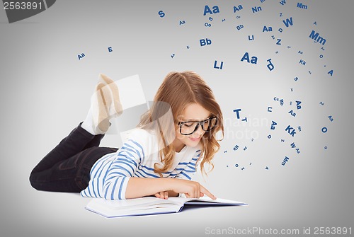 Image of smiling little student girl lying on the floor