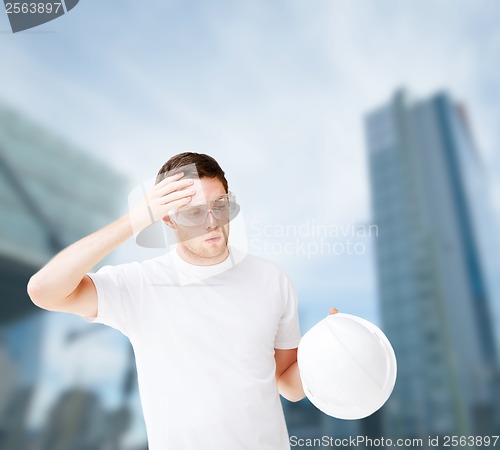 Image of male architect in safety glasses taking off helmet