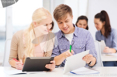 Image of two smiling students with tablet pc and notebooks