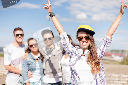 Image of teenage girl with headphones and friends outside