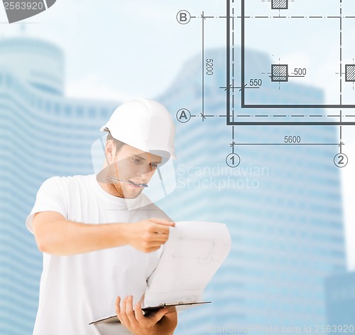 Image of male architect in helmet looking at blueprint