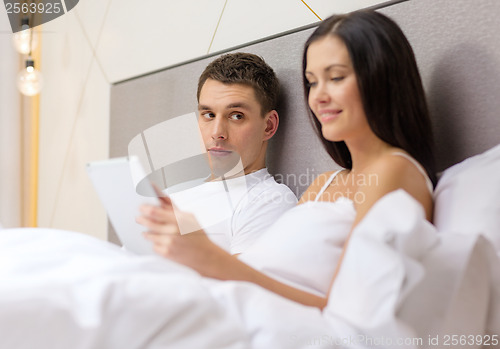 Image of smiling couple in bed with tablet pc computers