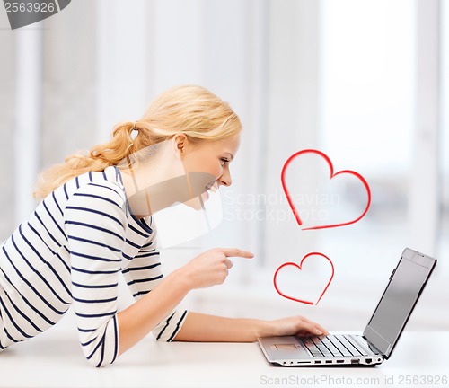 Image of smiling student girl pointing her finger at laptop