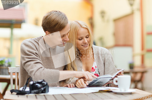 Image of couple with map, camera, city guide and coffee
