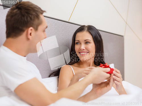 Image of man giving woman little red gift box